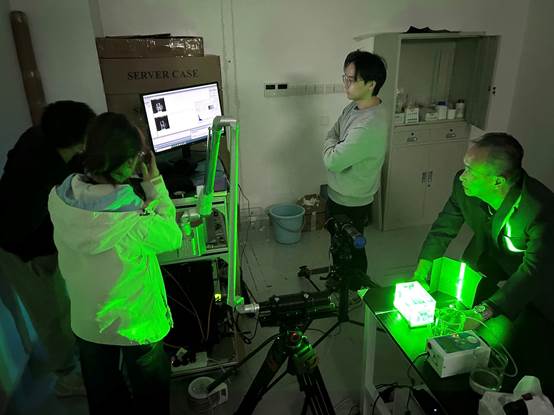 A group of people in a room with green light
Description automatically generated